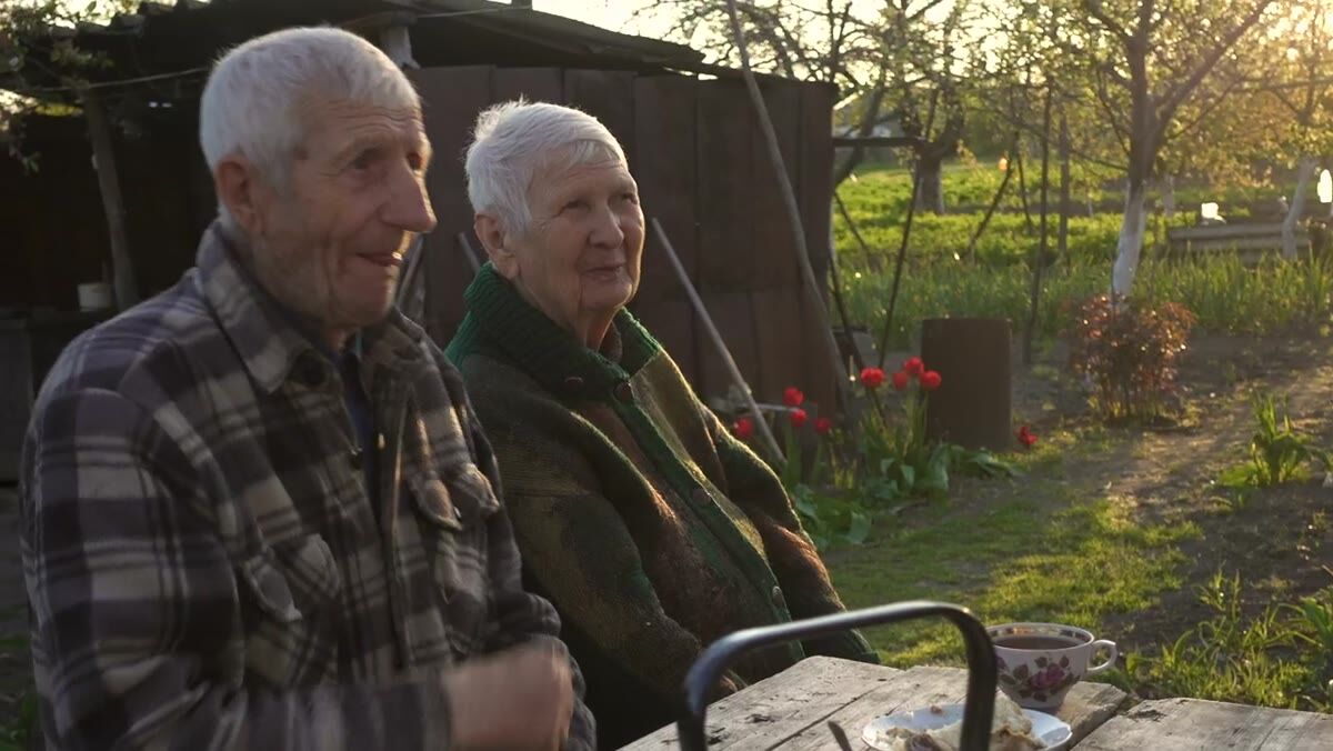 An older couple sitting together in a sunny garden