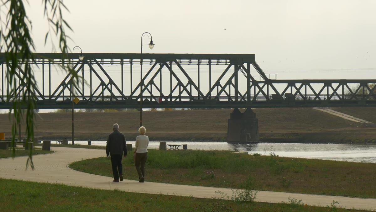 An older couple walking together beside the water on a mid-Michigan afternoon