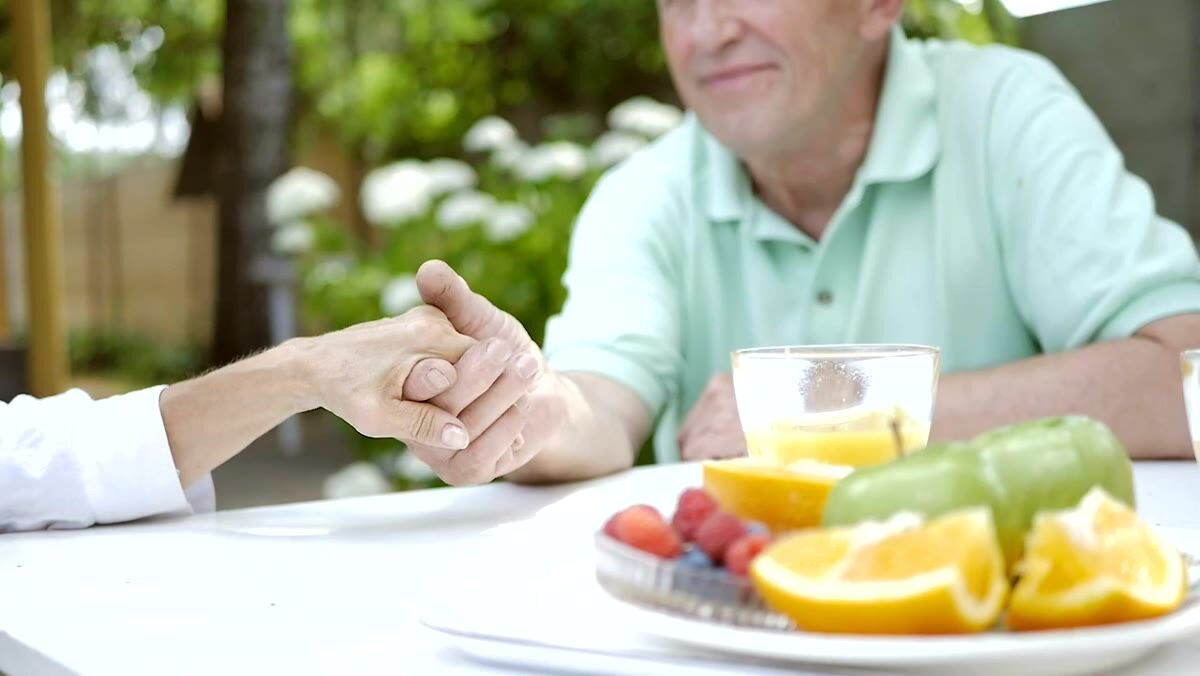 An older person's hand held gently across a kitchen table
